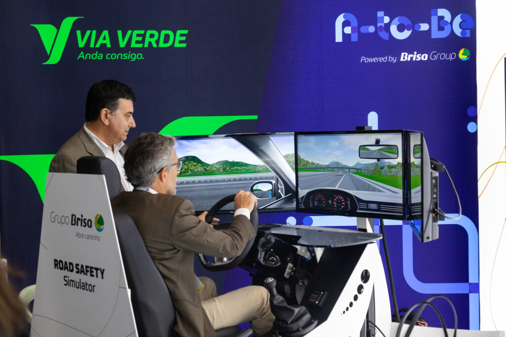 A man in a suit driving a simulated car at an exhibition